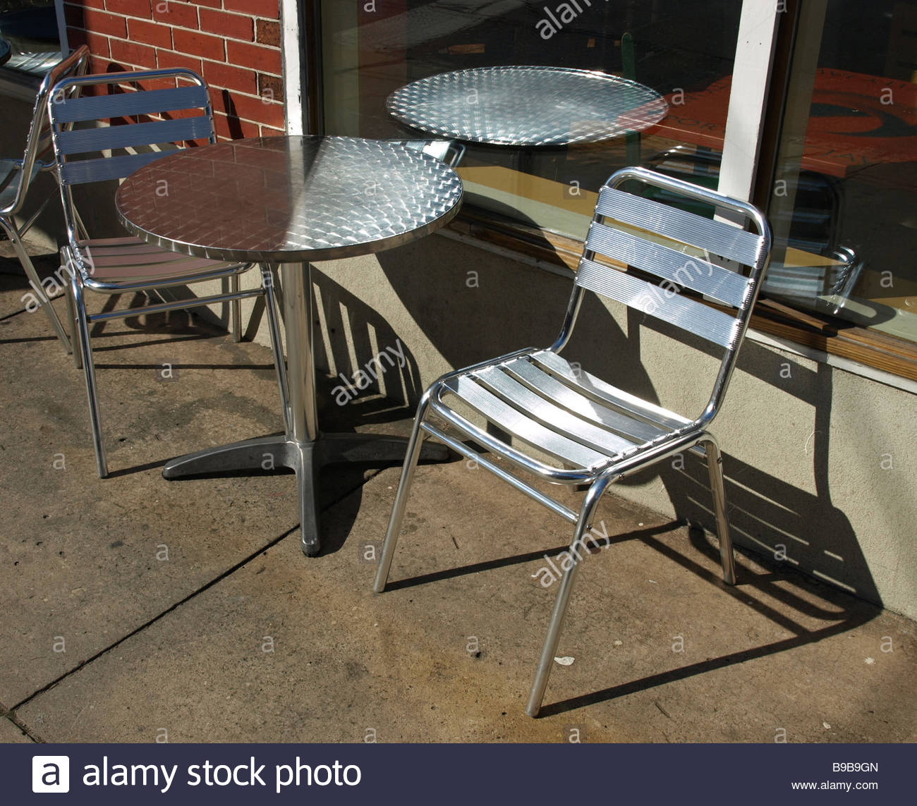 outdoor metal table chairs on cement walk near brick wall modern steel B9B9GN