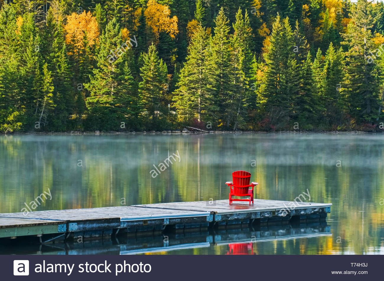 fauteuil muskoka sur dock a l automne feuillage couleur reflete dans l eau du lac tranquille de clear lake parc national du mont riding manitoba canada t74h3j