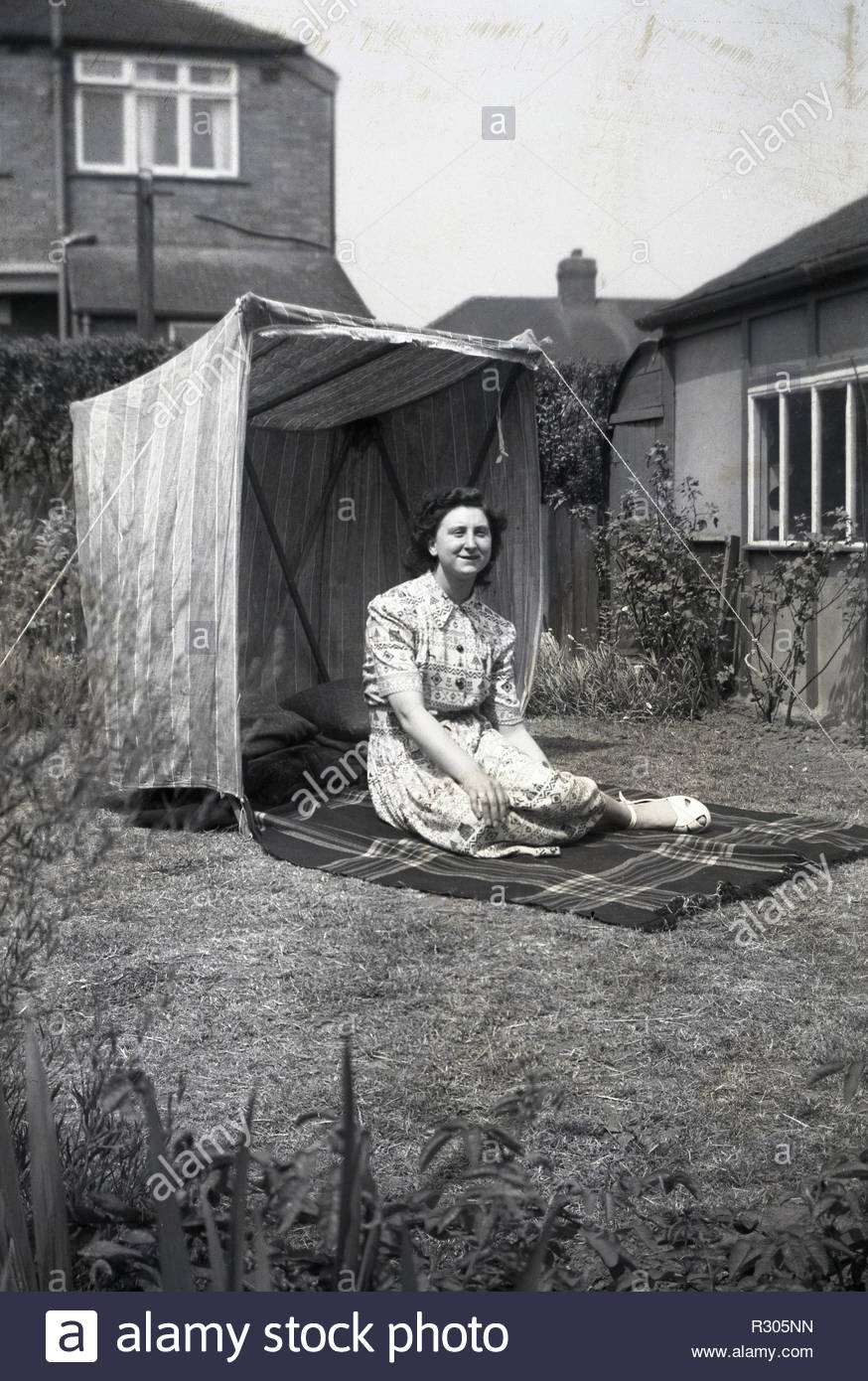 annees 1950 historiques femme assise sur un tapis a l exterieur dans un jardin a cote d une tente ou un abri du vent england uk image