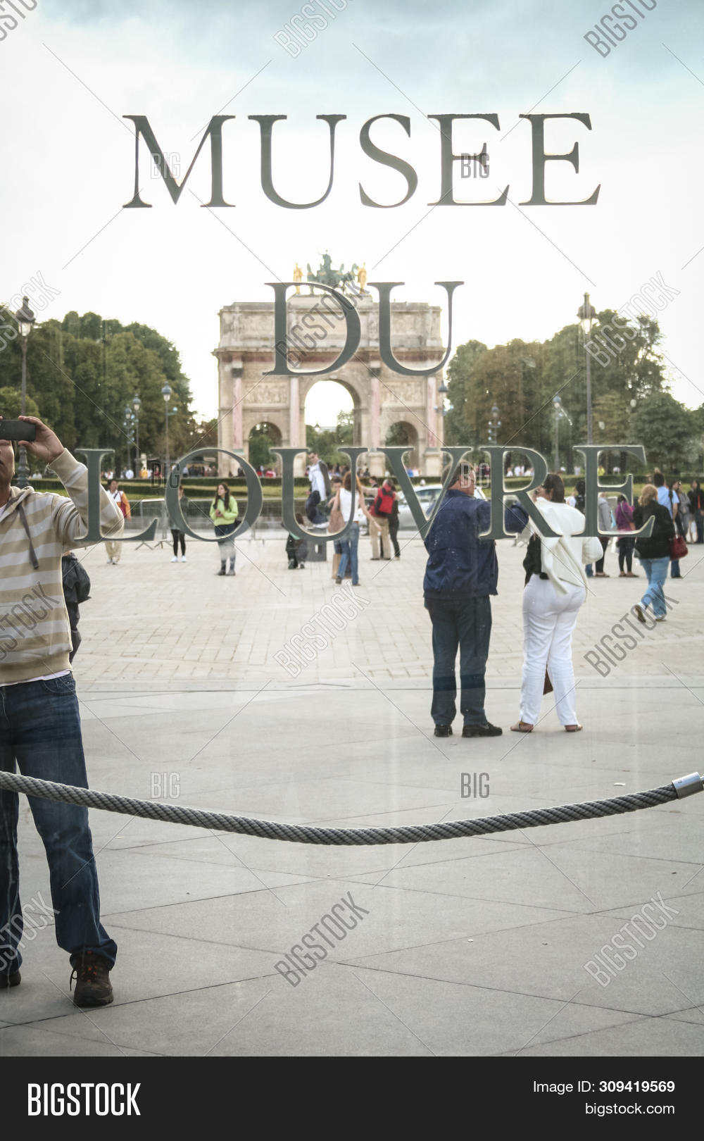 stock photo paris, france july 23, 2011: tourist taking pictures behind the logo of louvre museum (musee du lo